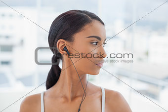 Pensive pretty model in sportswear listening to music