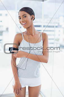 Smiling pretty model in sportswear changing song on her mp3