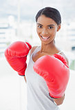 Competitive cheerful model wearing red boxing gloves