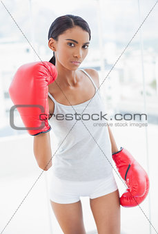 Serious competitive model with boxing gloves threatening camera