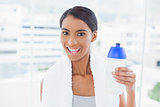 Cheerful sporty model with towel on shoulders holding flask