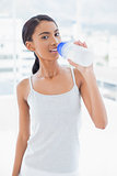 Smiling sporty model drinking water from her flask