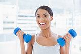 Cheerful sporty model exercising with dumbbells