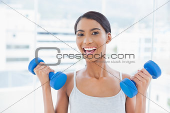 Cheerful sporty model exercising with dumbbells