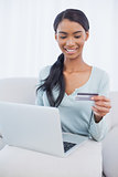 Cheerful attractive woman using her laptop to buy online
