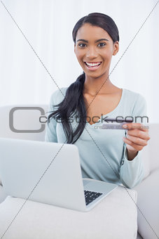 Smiling attractive woman using her laptop to buy online