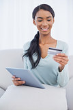 Cheerful attractive woman using her tablet pc to buy online