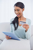Surprised attractive woman using her tablet pc to buy online