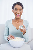 Smiling attractive woman eating popcorn while watching tv