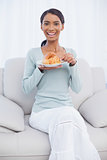 Smiling attractive woman eating croissant