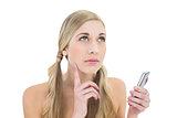 Pensive young blonde woman holding a mobile phone