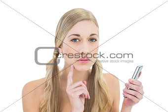 Thoughtful young blonde woman holding a mobile phone
