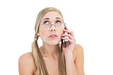 Anxious young blonde woman looking up while calling on phone