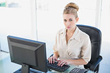 Stern young blonde businesswoman using a computer