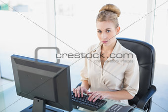 Stern young blonde businesswoman using a computer