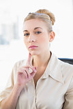 Thinking young blonde businesswoman looking at camera