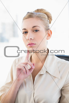 Thinking young blonde businesswoman looking at camera