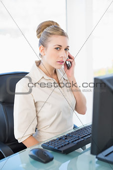 Serious young blonde businesswoman calling with her mobile phone