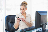 Concentrated young blonde businesswoman texting with her mobile phone