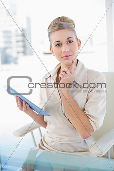 Pensive young blonde businesswoman holding a tablet pc