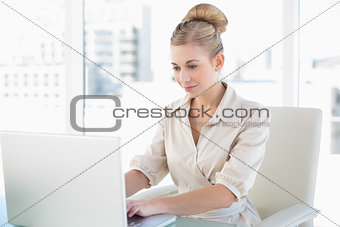 Concentrated young blonde businesswoman using a laptop