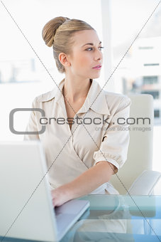 Thoughtful young blonde businesswoman using a laptop