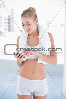 Content young blonde model texting on her mobile phone