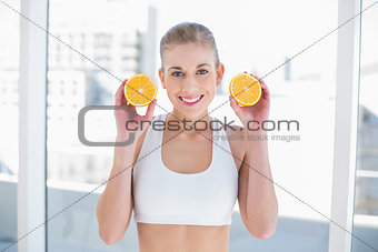 Attractive young blonde model holding two halves of an orange