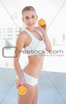Motivated young blonde model holding two halves of an orange
