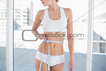 Close up of a fit woman measuring her waist