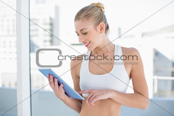 Joyful young blonde model using a tablet pc