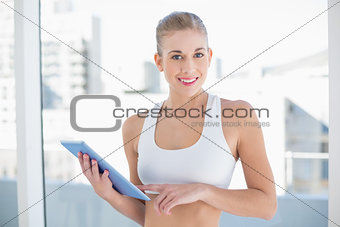 Cheerful young blonde model holding a tablet pc
