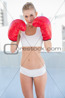 Serious young blonde model exercising with boxing gloves