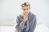 Attractive relaxed blonde woman in hair curlers yawning