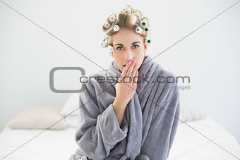Attractive relaxed blonde woman in hair curlers yawning