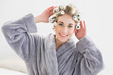 Smiling relaxed blonde woman adjusting her hair curlers