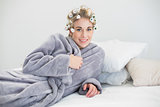 Happy relaxed blonde woman in hair curlers lying on her bed