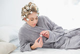 Concentrated relaxed blonde woman in hair curlers opening a pot of nail polish