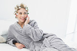 Cheerful relaxed blonde woman in hair curlers calling with her mobile phone