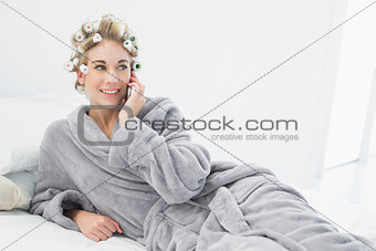 Cheerful relaxed blonde woman in hair curlers calling with her mobile phone