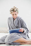 Pretty relaxed blonde woman in hair curlers using a tablet pc