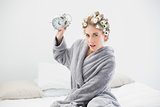 Angry blonde woman in hair curlers throwing her alarm clock