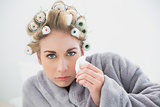 Troubled blonde woman in hair curlers crying and using tissues