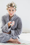 Lovely relaxed blonde woman in hair curlers using a remote control