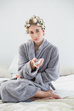 Thoughtful relaxed blonde woman in hair curlers using a remote control