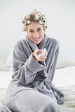 Joyful relaxed blonde woman in hair curlers using a remote control