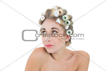 Thoughtful blonde model in hair curlers looking away