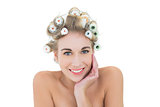 Cheerful blonde model in hair curlers holding her head