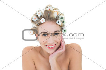 Cheerful blonde model in hair curlers holding her head