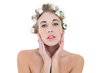Thinking blonde model in hair curlers holding her head